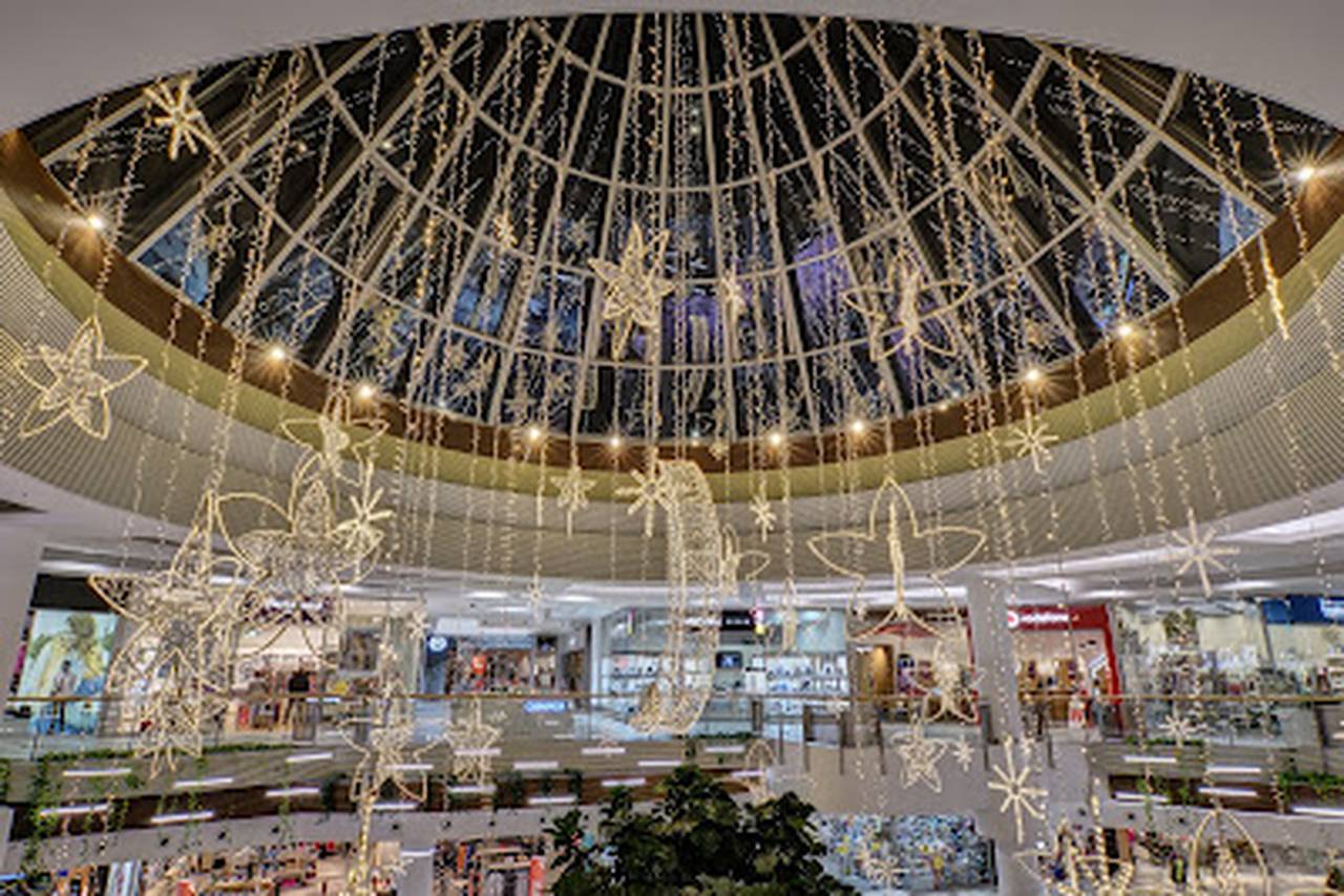 Prosklená kopule nákupního centra vyzdobená visícími svítícími hvězdami a měsícem.